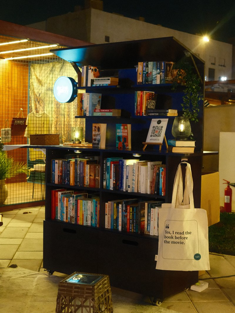 A cozy outdoor bookshelf filled with books, illuminated by soft lighting at night.
