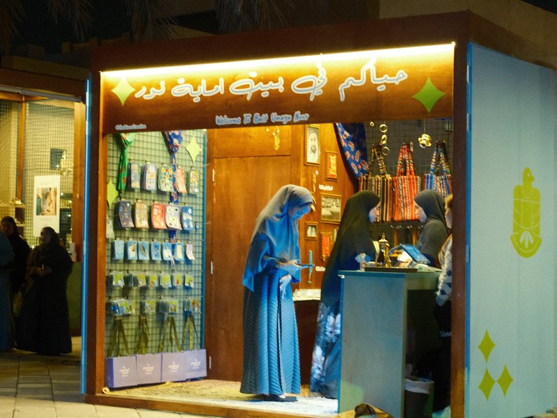 Women in traditional attire shopping at a brightly lit store with colorful displays.