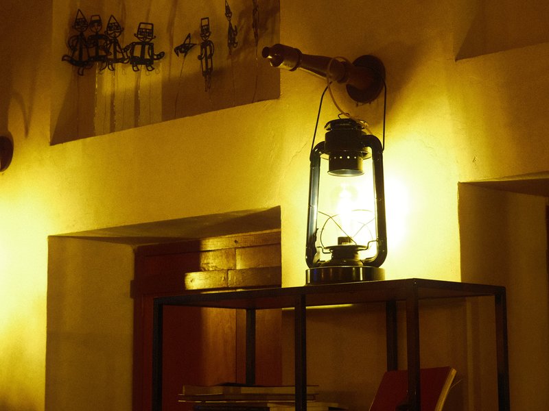 A vintage lantern on a shelf, casting warm light in a cozy indoor setting.