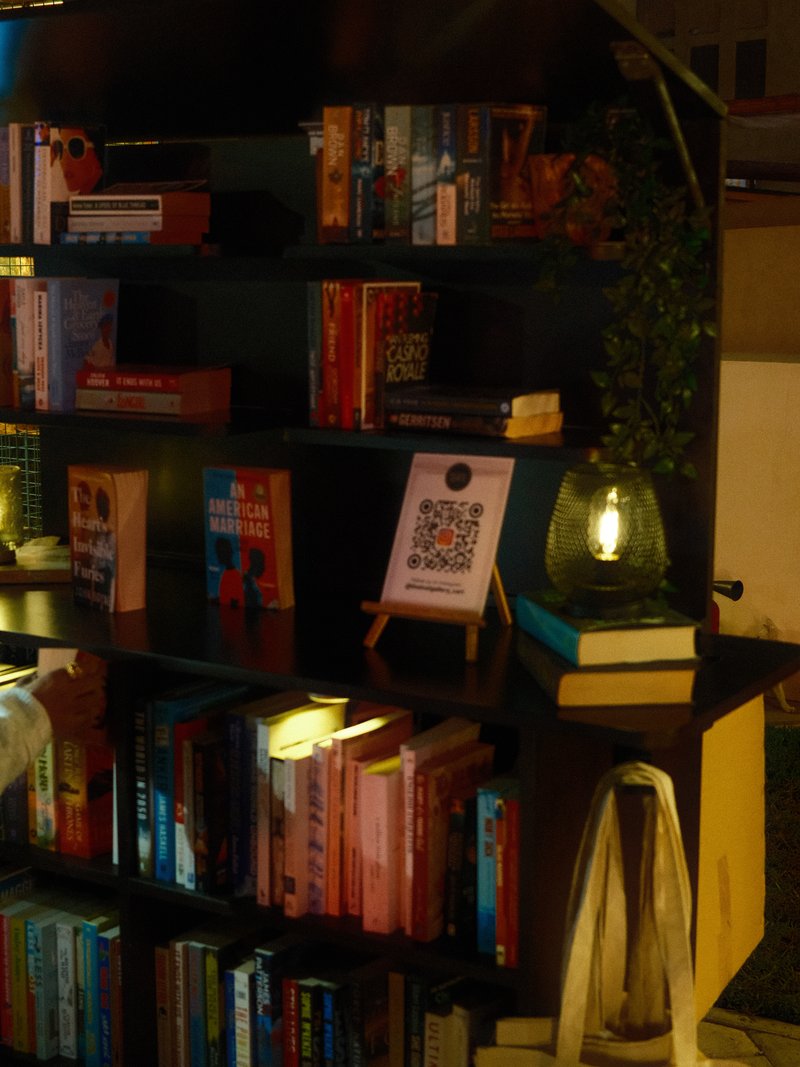 A cozy bookshelf filled with colorful books, a lamp, and a QR code on a small easel.