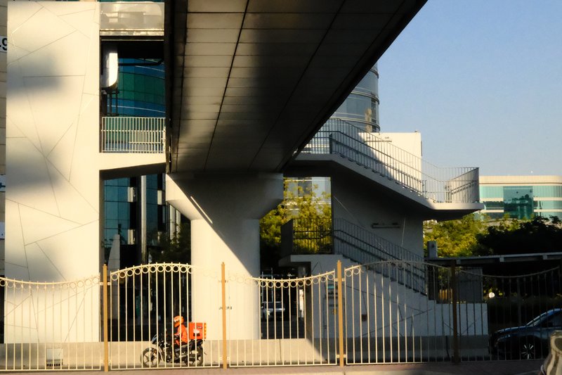 A modern architectural structure with a cyclist in the foreground, showcasing geometric lines and shadows.