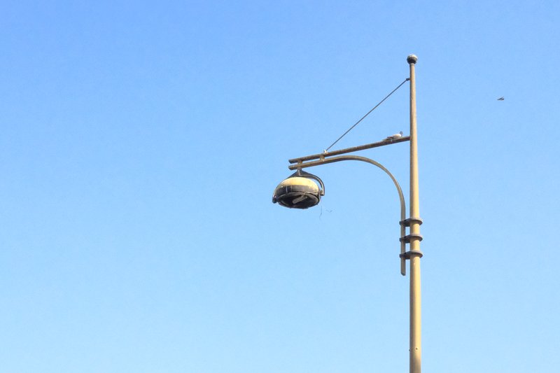 A street lamp against a clear blue sky, showcasing its design and structure.
