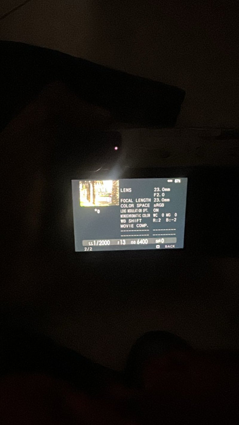 A camera display showing settings in low light with a hand holding the camera.