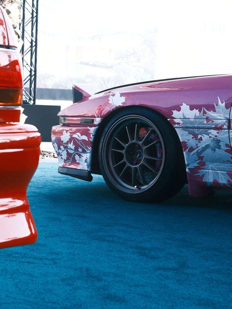 Close-up of two cars, one with a colorful design and the other in red, on a blue carpet.