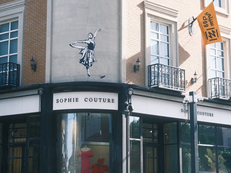 A street corner featuring a mural of a dancer and a boutique named Sophie Couture.