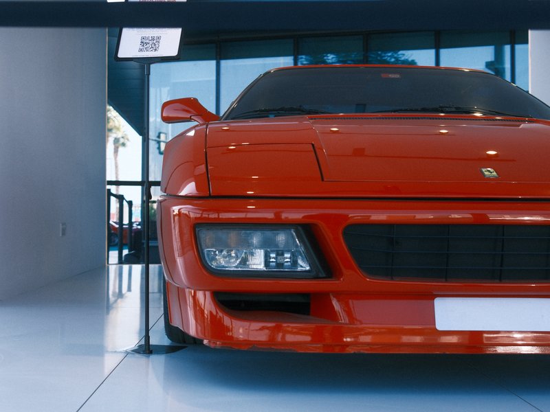 A bright red sports car displayed in a modern showroom with sleek lines and reflective surfaces.