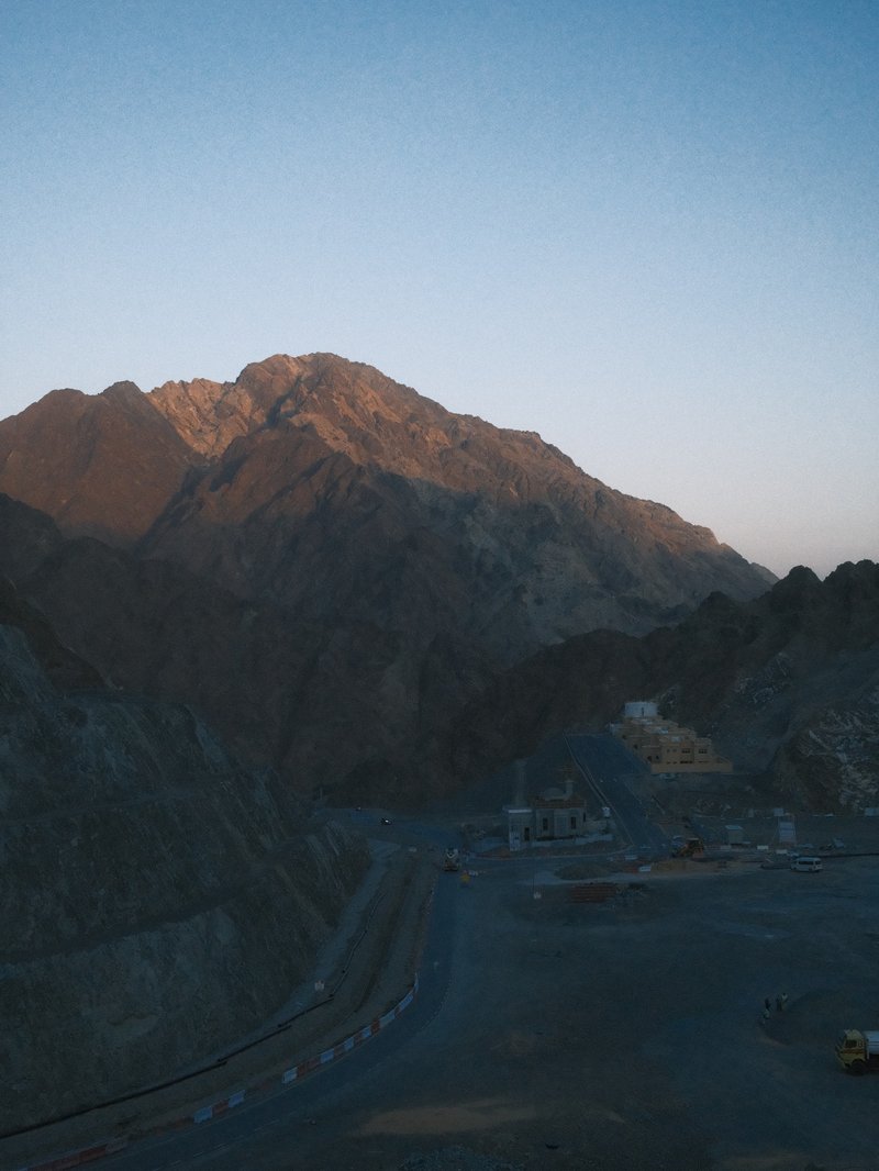 A mountain landscape at dusk with soft light illuminating the peaks and shadows in the valleys.