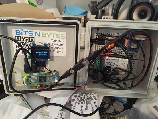 Picture of an outdoor project box with a Raspberry Pi Zero, screen, and meshcore / meshtastic radio mounted inside.