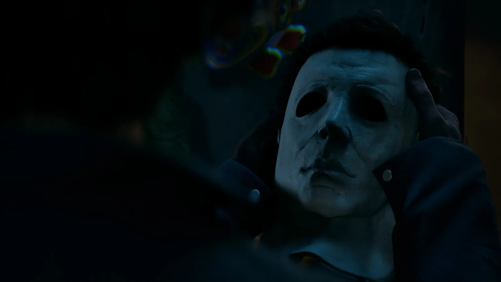 Michael Myers standing in a foggy Haddonfield street at night, lit by porch lights
