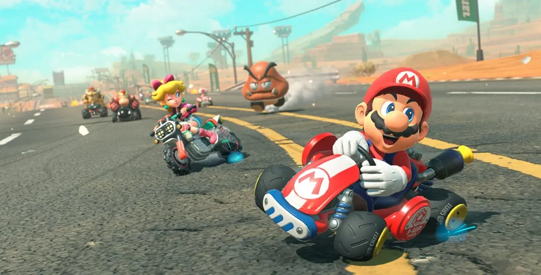 Mario Kart World gameplay screenshot from the Nintendo store page showing a wide open road race with 24 drivers and a chain chomp item, official Nintendo promo art.
