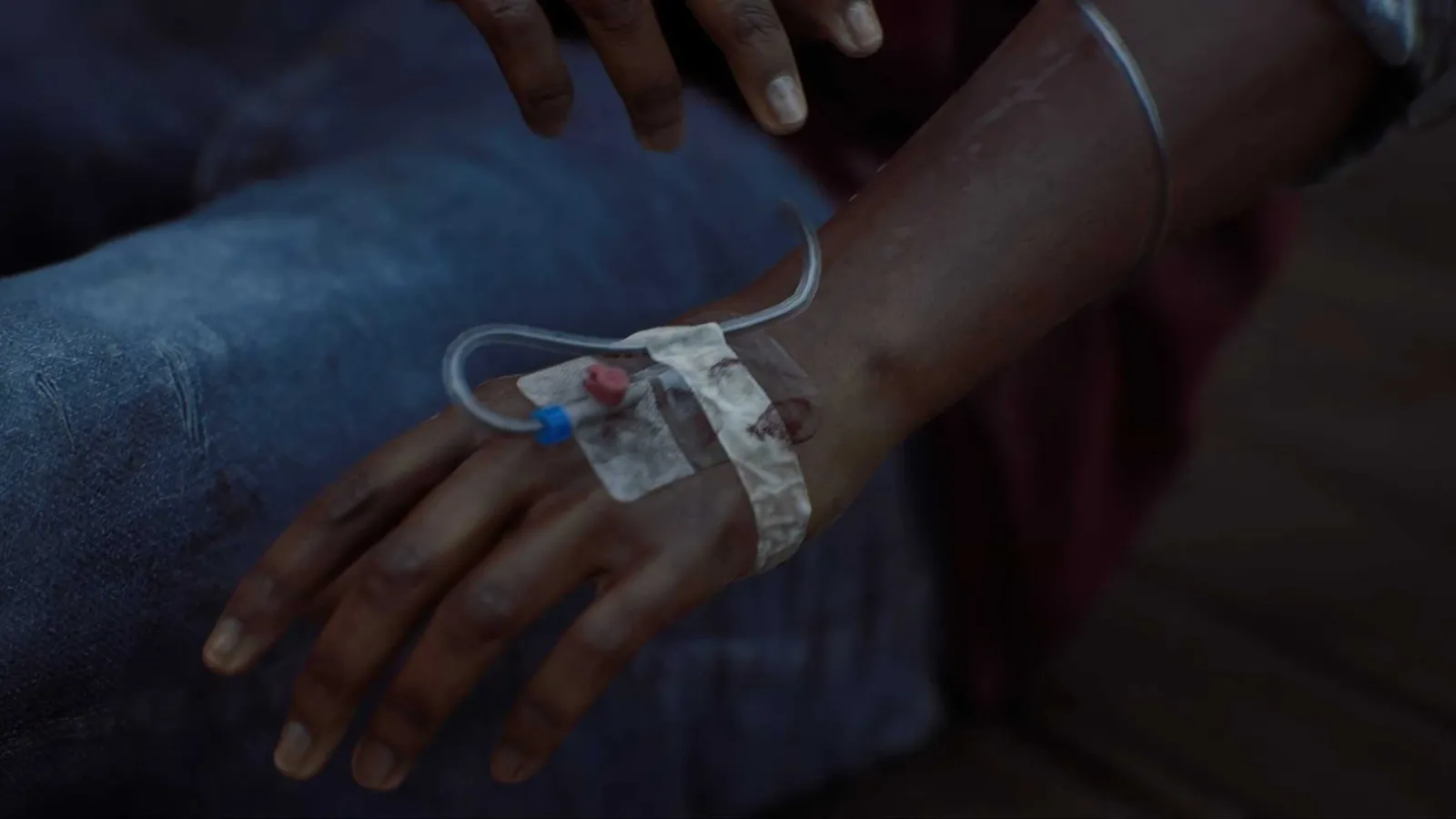 Silent Hill Townfall protagonist Simon looking down at his hand, with an IV line feeding into a port.