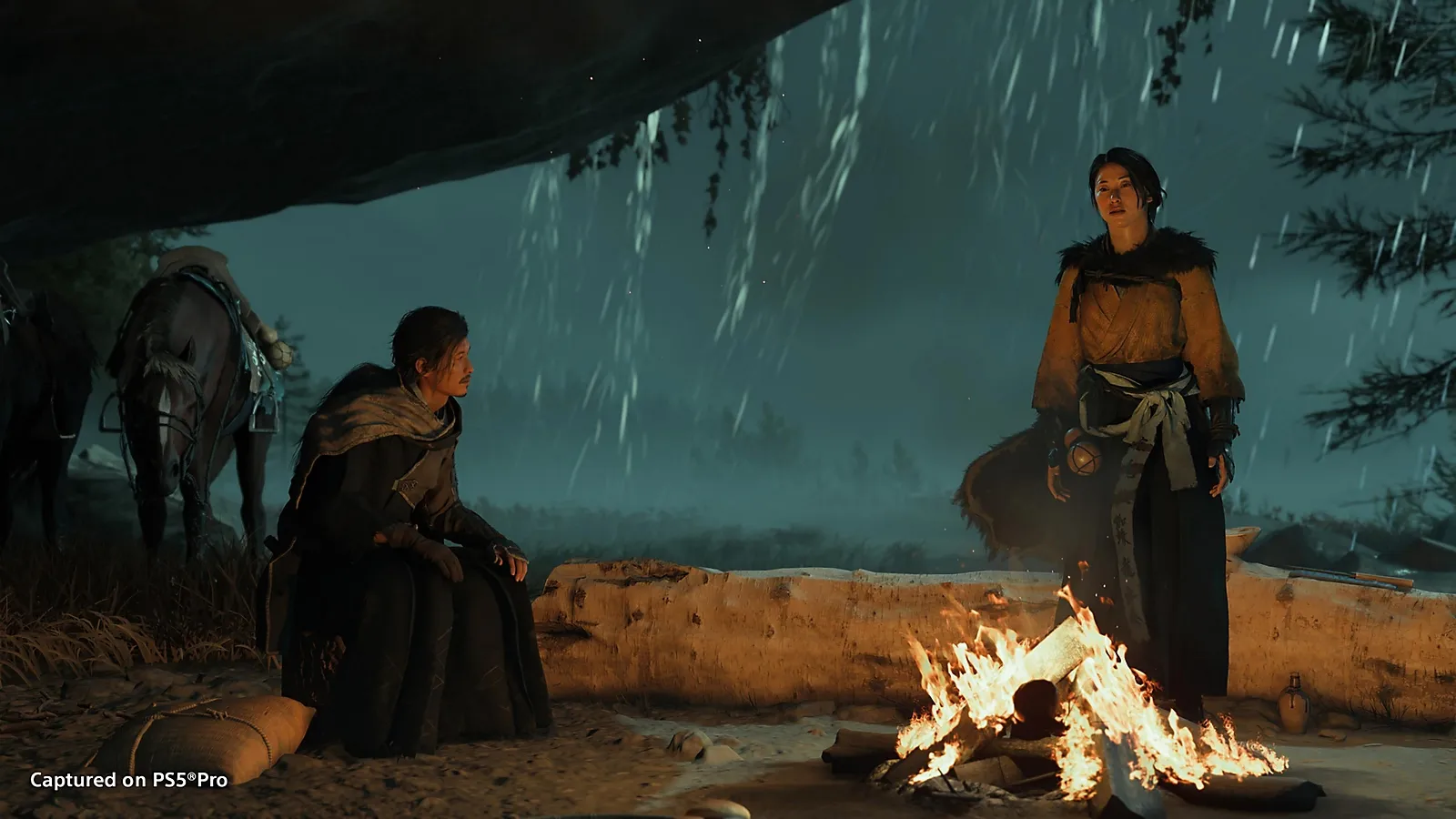 Atsu and another character sheltering from rain around a camp fire in Ghost of Yotei