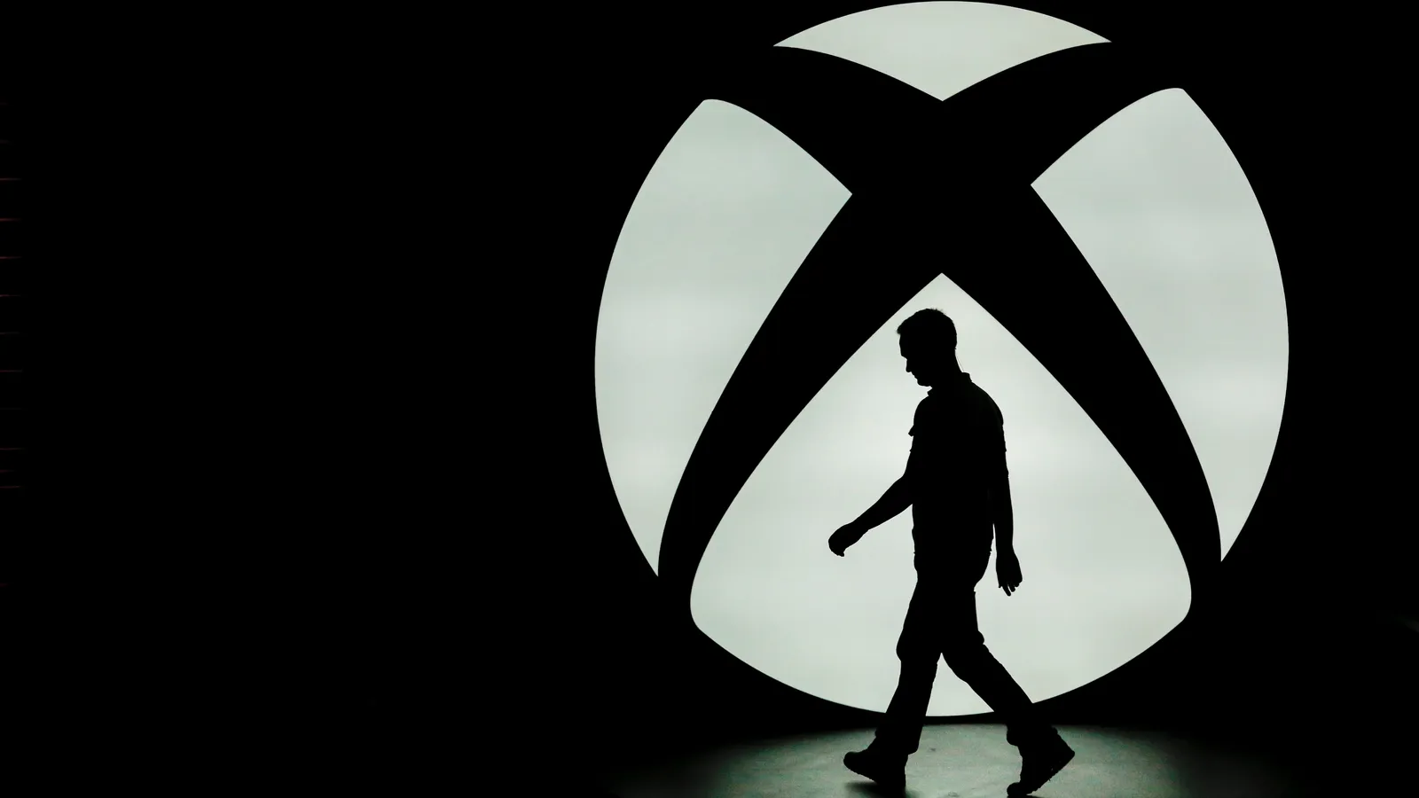 A silhouette walks past the Xbox One logo at the Xbox E3 media event in Los Angeles, California, on June 9, 2014