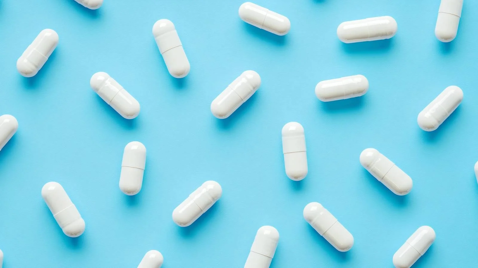 Clinical White Capsules on Blue Background — free download from Dotvec