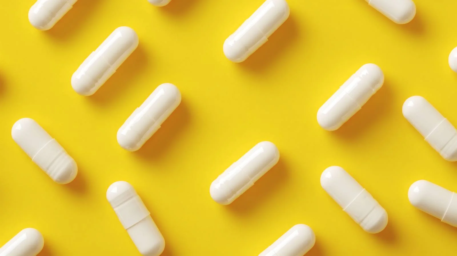 Clinical white capsules on yellow backdrop — free download from Dotvec