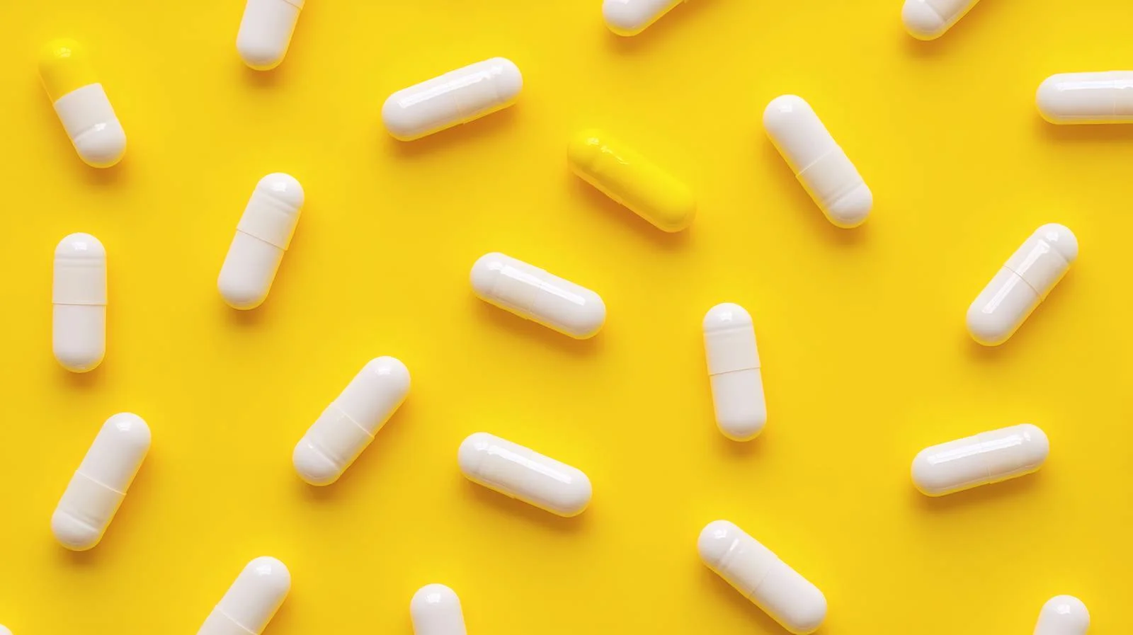 White Capsules on Vibrant Yellow Background — free download from Dotvec