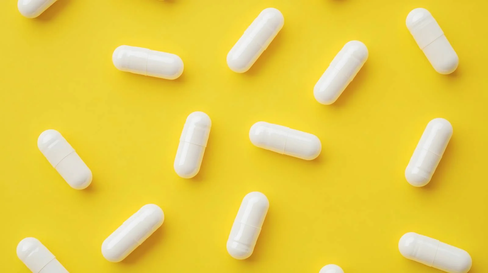 Vibrant Yellow Background with White Medicine Capsules — free download from Dotvec