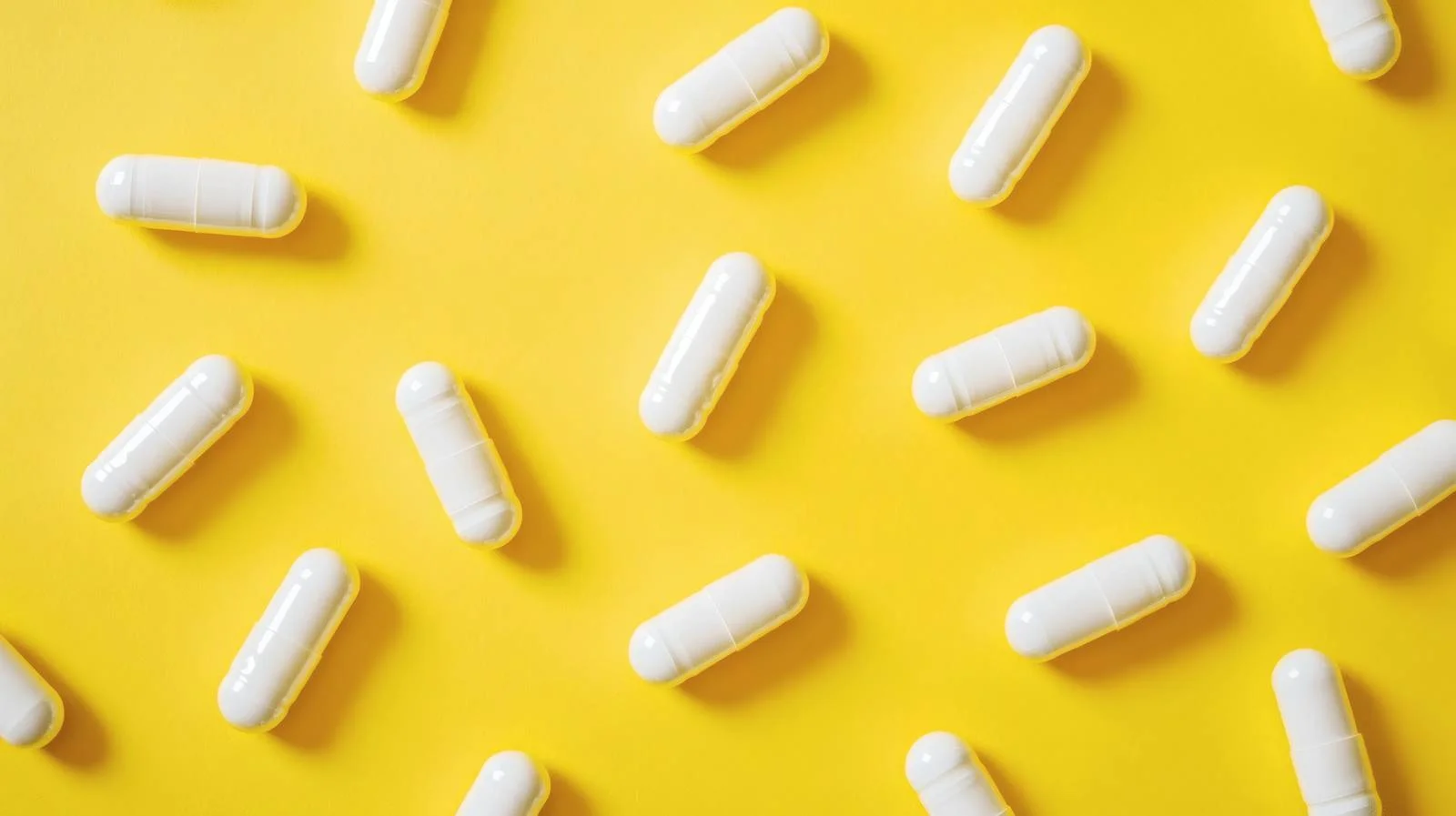 White Capsules on Vibrant Yellow Background — free download from Dotvec