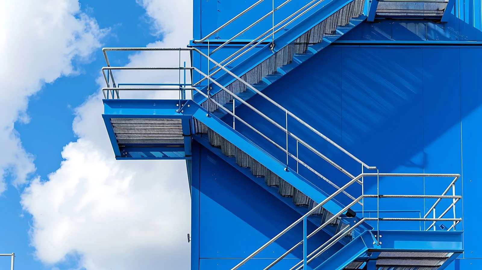 Industrial metal stairs leading to blue building — free download from Dotvec