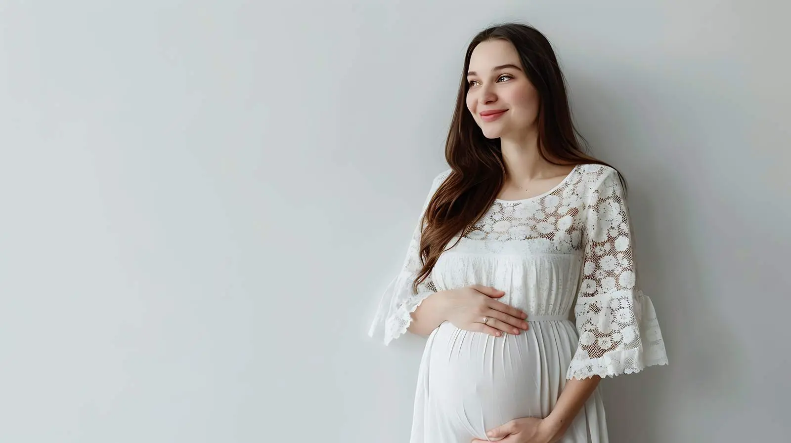Pregnant Woman Posing Near White Wall — free download from Dotvec