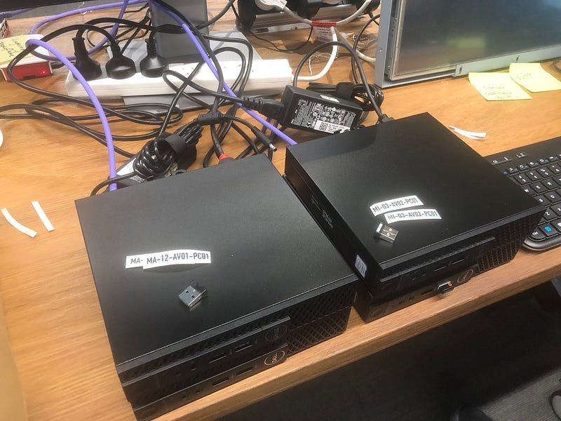 two-black-laptops-with-cables-on-wooden-desk