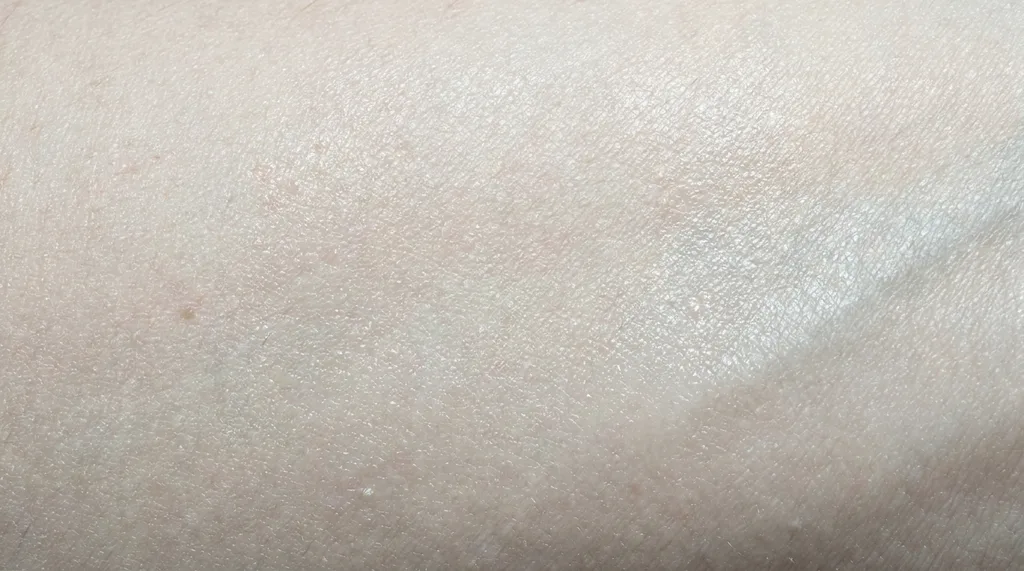 An extreme macro photograph of skin texture showing subtle surface irregularity and micro-level moisture gradients, clinical and honest, Extreme macro photograph of human forearm skin surface showing fine texture detail, subtle moisture variation across the surface, visible micro-topography of the stratum corneum, shot on Nikon Z9 with 105mm f28 macro lens, cool clinical overhead light at 5600K with slight diffusion, color palette of pale ivory, cool beige, and neutral shadow tones, mood is honest and scientific, no filters or beautification, hyper-realistic editorial photography, 8k, sharp focus, professional color grading, NO text, NO illustration, NO cartoon, NO 3d render