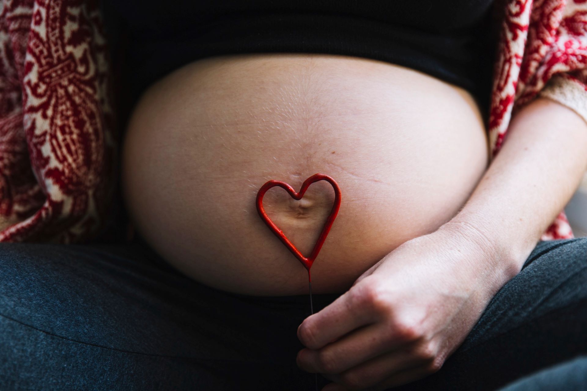 mulher com barriga de gr&aacute;vida e um cora&ccedil;&atilde;o