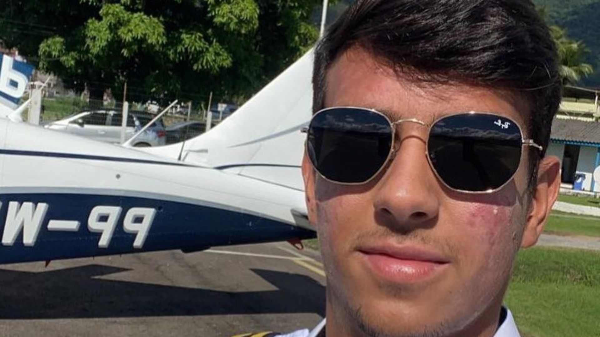 Menino posando para uma foto com um avi&atilde;o ao fundo