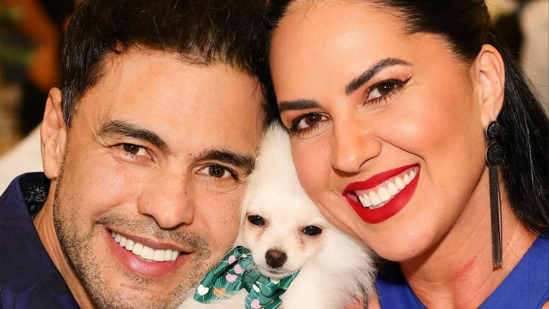 Casal sorrindo com um cachorro