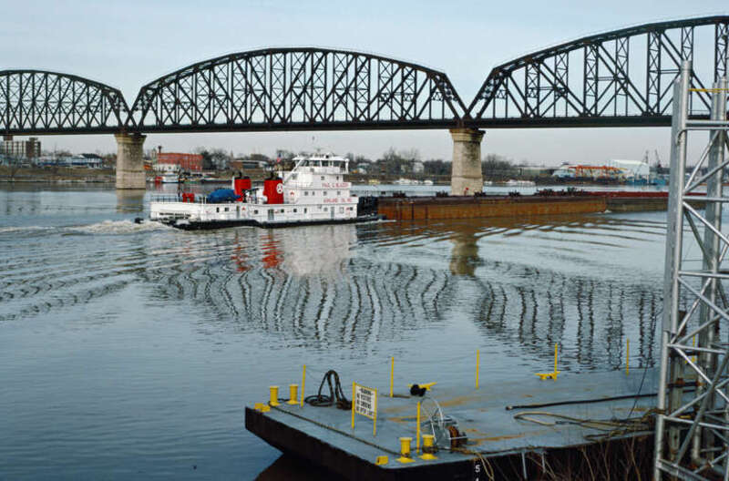 Looking NNE from Ashland asphalt terminal just above JFK Bridge.
Black barge with gray deck is permanently moored next to pylons.
Towboat "Paul G. Blazer" (doc. # 918951) upbound at Big Four Bridge.
.
"Paul G. Blazer" (150x45, twin Cat 3606 diesels,