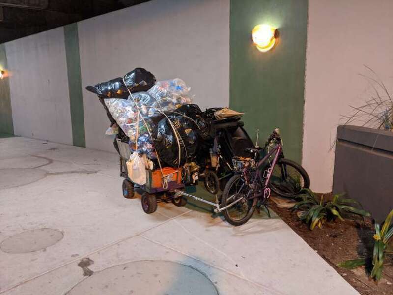 A pile of goods in shopping carts and a bicycle, likely owned by a homeless person, on the south side of the pedestrian underpass where CA-17 passes over Campbell Ave in Campbell, CA.