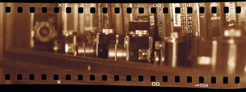 
500px provided description: Shot with 35mm film in a quarter plate film holder on an Anaversary Speed Graphic [#black and white ,#camera ,#panoramic ,#sprockets ,#book case]