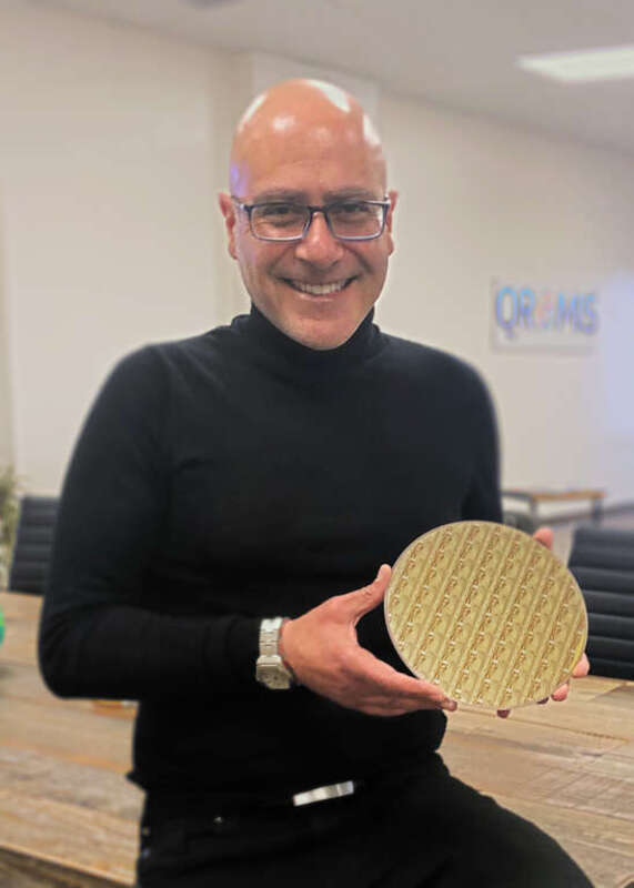 Cem Basceri, QROMIS president and CEO, displays a 200 mm diameter 650V, E-mode gallium nitride (GaN) discrete power device wafer on a QST® (QROMIS Substrate Technology) substrate. (Courtesy photo by QROMIS)