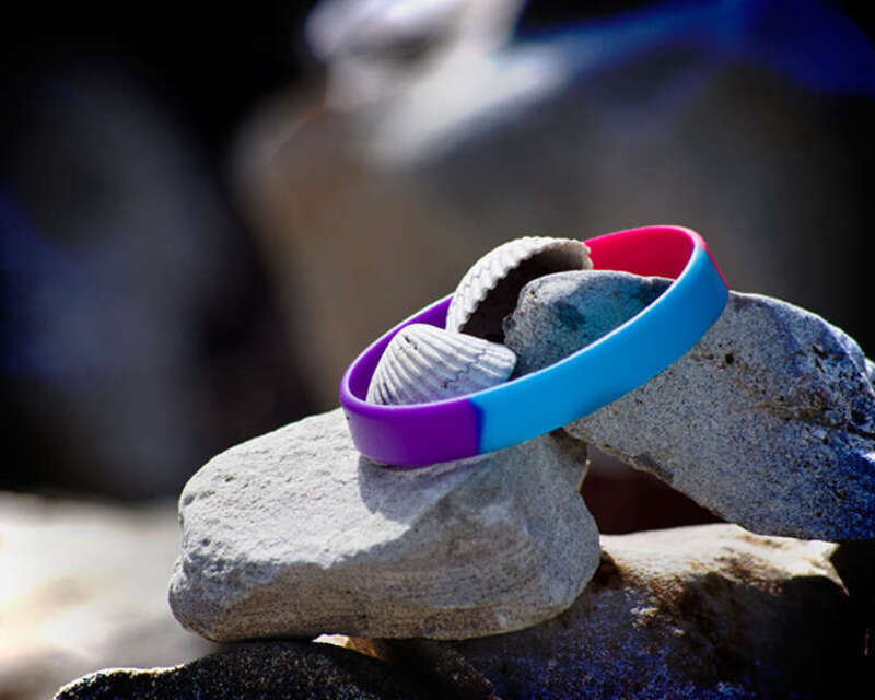 Colored wristband and seashells placed on top of a stack of rocks at the bottom of the seawall in Galveston
