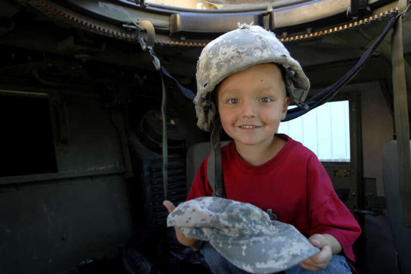 Four-year-old Syxx Bullplume of Tacoma, Wash. sits inside a humvee with a helmet on his head and a patrol cap in hand, Sept. 25, at the Lakewood Towne Center during "Lakewood Salutes." Soldiers with 4th Stryker Brigade Combat Team, 2nd Infantry