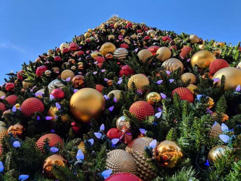 Photograph of the large, heavily-ornamented artificial Christmas tree in the center of the plaza in the Spectrum Center in Irvine, CA. Taken from the position immediately at the foot of the tree, looking up.