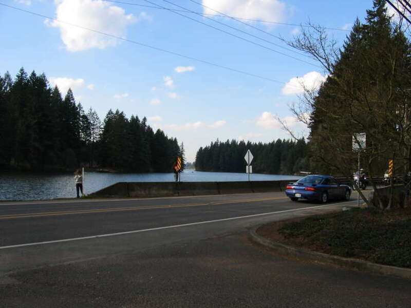 Children fish while standing on the SR 500 bridge over the intersection of Lacamas Lake and Round Lake in Washington. The camera was positioned in the parking lot of Lacamas Park and was facing west.