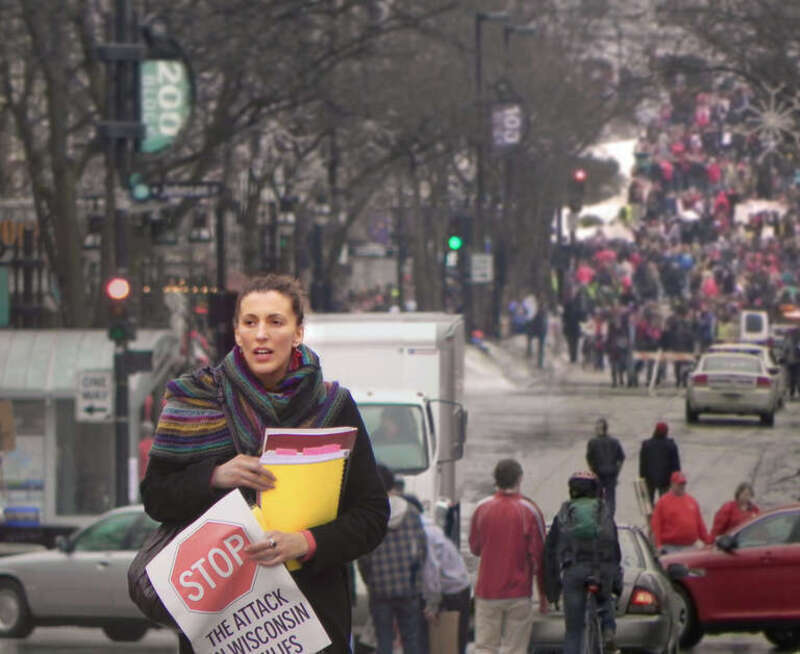 Unidentified woman on State Street in Madison, Wisconsin on 2-15-2011 walking away from the State Capitol holding a protest sign