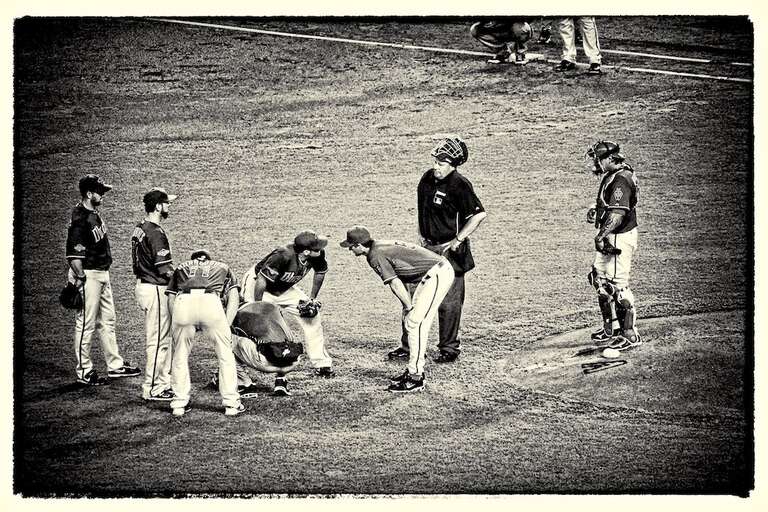 Jason Marquis took a line drive to the leg. In this image he is being checked out by staff and team mates. In the later inning he collapsed with a broken shin bone.