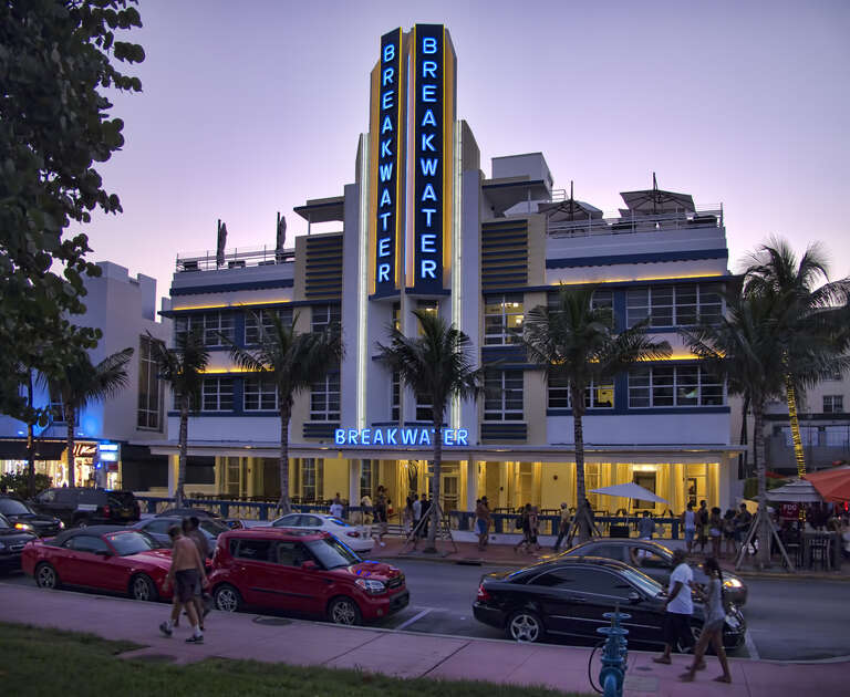 The just-restored Breakwater on Ocean Drive in South Beach is a Streamline Moderne [horizontal emphasis and sleek] building with the largest porch on Ocean Drive.
On Google Earth:

Breakwater Hotel  25°46'47.81"N, 80° 7'51.21"W