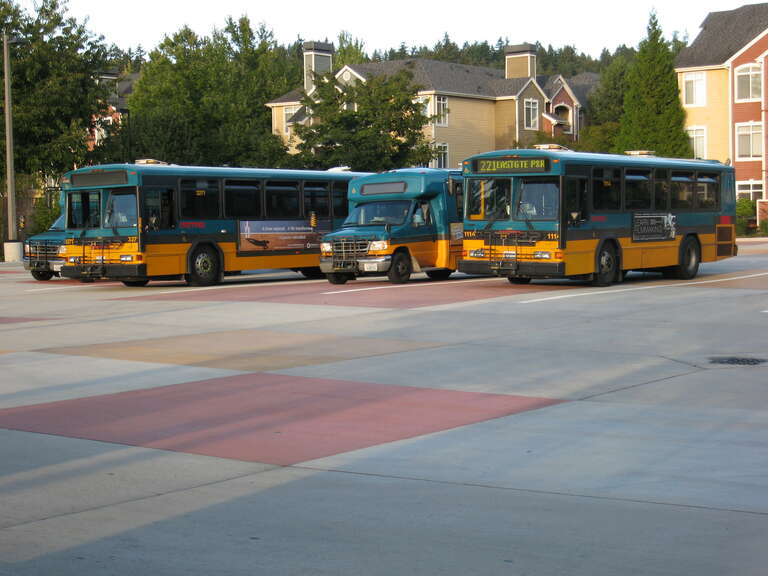 Five coaches lay over at Redmond Transit Center.  Three are Ford vans (one not visible), and one each 40' Gillig PHANTOM and 30' Gillig PHANTOM