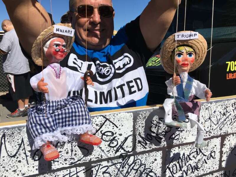 A man holds puppets representing Donald Trump and Hillary Clinton in Las Vegas, Nevada, a few kilometers from the site of the third presidential debate.