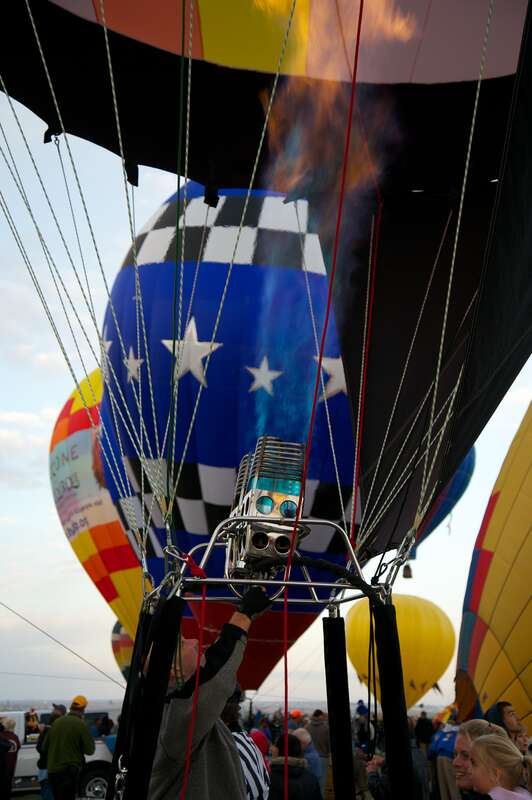 A balloon pilot warms his balloon for lift-off. Albuquerque International Balloon Fiesta, 2012. Over 750 ballons on site.