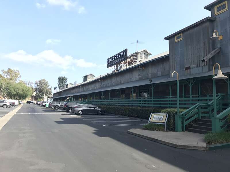 Photo of the southern half of the building with a historical marker seen in the background (middle right).