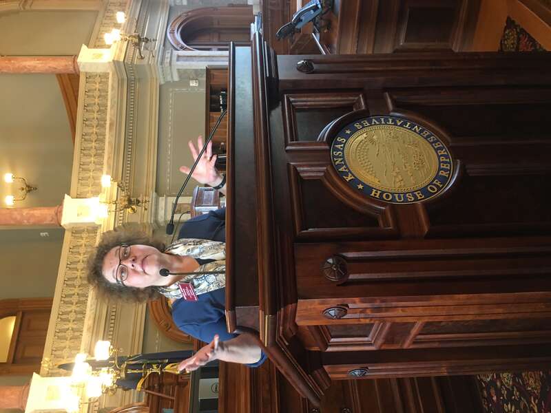 Kansas State Representative Monica Murnan speaks at the dais in the Kansas House of Representatives chamber