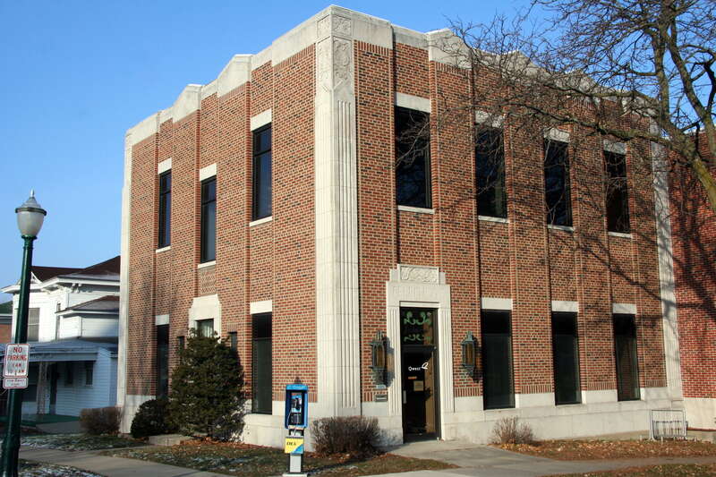 Qwest telephone exchange building on the corner of Main and Court Streets in Decorah, Iowa, with a public phone in front and the Norwegian word "Velkommen" painted above the door.