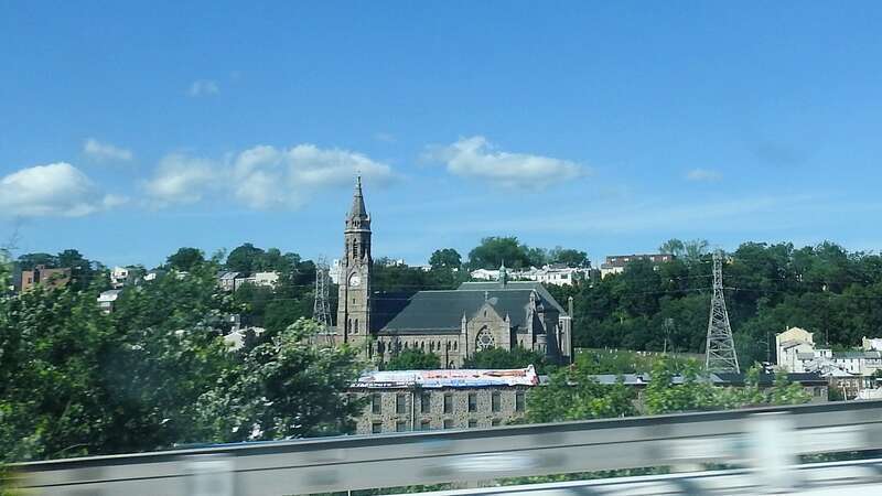 Looking northeast out the window of a passing bus, across the river.