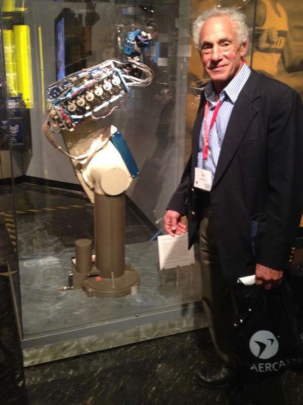 w:Victor Scheinman at the w:MIT Museum. The robot in the display case is a PUMA robot, which was developed by Scheinman. An experimental hand developed by Ken Salisbury is attached to the arm.
