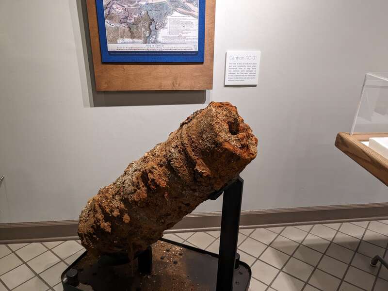 A river-damaged cannon, labelled "RC-01", intentionally un-conserved
