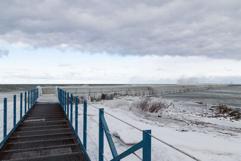 A view from Port Austin Breakwater Pier, off of Veterans Waterfront Park, in Port Austin, Michigan. The water has frozen over the pier's deeper into the lake parts. This image was taken in winter.